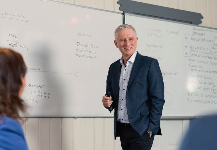 Steinar Lunde står ved en tavle med notater om utvikling og modenhet, mens en deltaker lytter.